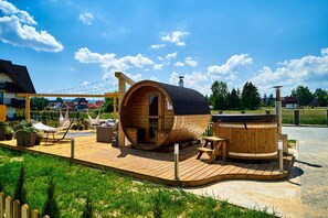 A wooden cabin with a curved roof, a hot tub, and a hammock on a wooden deck. - Resorts Sun&Snow Białka Tatrzańska P (Bialka Tatrzanska)