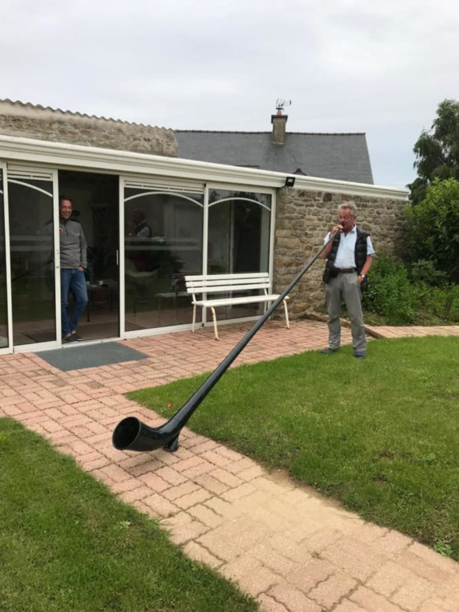 A house with a patio, a white bench, and a large black object on the ground.