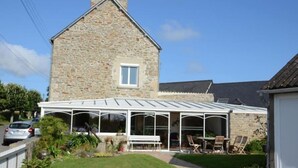 Een stenen huis met een overdekte patio, compleet met een tafel en stoelen.