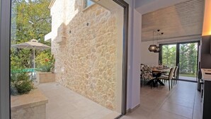 Ein modernes Interieur mit einer Steinwand, einem Essbereich mit Tisch und Stühlen sowie Blick ins Freie.