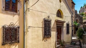 Una calle estrecha con un edificio que tiene un pequeño arco y un toldo a rayas rojas y blancas.