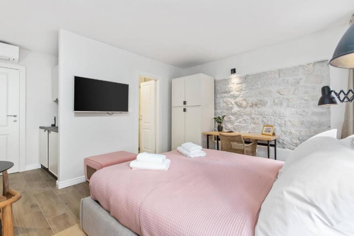 Un dormitorio moderno con una cama grande, un televisor de pantalla plana, un escritorio con silla y una pared decorada con piedra.