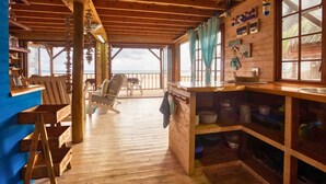 Une cabane en bois dotée d’une terrasse en bois, d’un coin bar et offrant une vue sur l’océan.