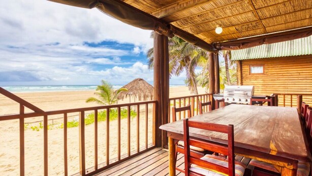 Une terrasse en bois avec une table et des chaises donnant sur une plage.