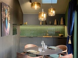 Un comedor moderno con una mesa redonda, sillas de madera e iluminación colgante.