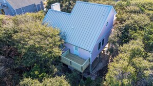 Une maison avec un toit métallique incliné, entourée d’une végétation luxuriante.