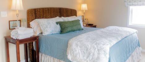 A bedroom with a bed, bedside tables, lamps, a ceiling fan, and a window with curtains.