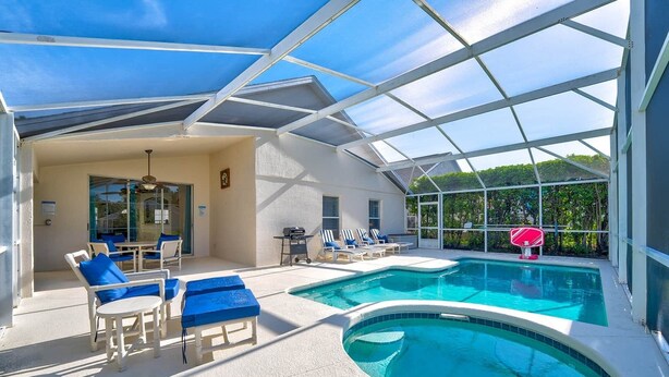 Un área de piscina con una estructura de cristal, sillones de descanso y un aro de baloncesto.