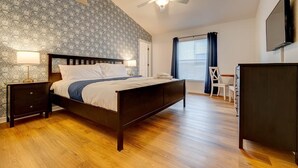 Un dormitorio con cama, mesitas de noche, escritorio, silla y televisor.