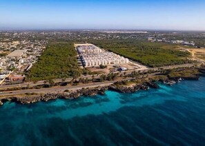 An aerial view of a coastal resort with a large beachfront property, a marina, and a dense residential area in the background. - Strandblick in der Residenz Apartment in Santo Domingo (Santo Domingo Este)