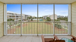 Un balcon donnant sur un quartier résidentiel, avec vue sur un terrain de jeux et des palmiers.