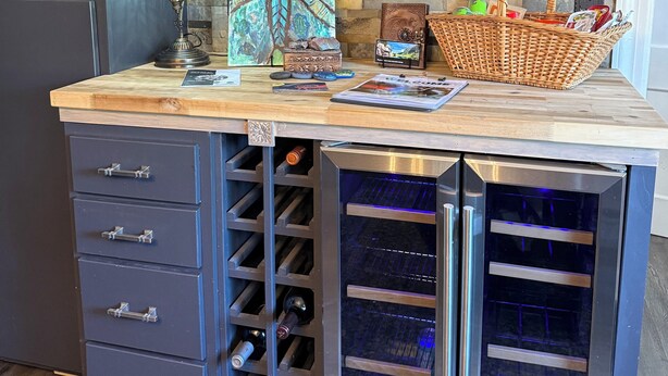 A kitchen with a wine rack, shelves with decorative items, and a wicker basket. - Musical Themed Duplex with Muskegon Lake Views (Muskegon)