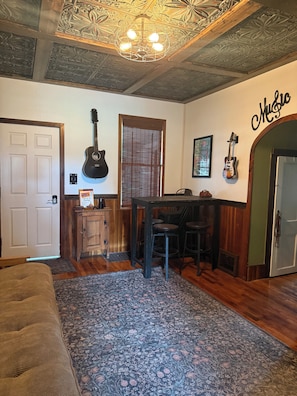 Une pièce avec un plafond en bois, une guitare, un coin bar et un panneau indiquant « Musique ».