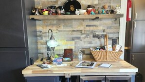 A kitchen with a wooden countertop, two drawers, a built-in wine cooler, and a shelf with various mugs and kitchen items. - Musical Themed Duplex with Muskegon Lake Views (Muskegon)