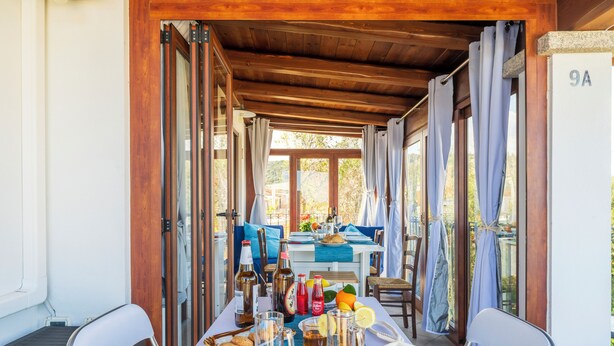 A covered outdoor dining area with a table set for two, featuring a variety of drinks and snacks.