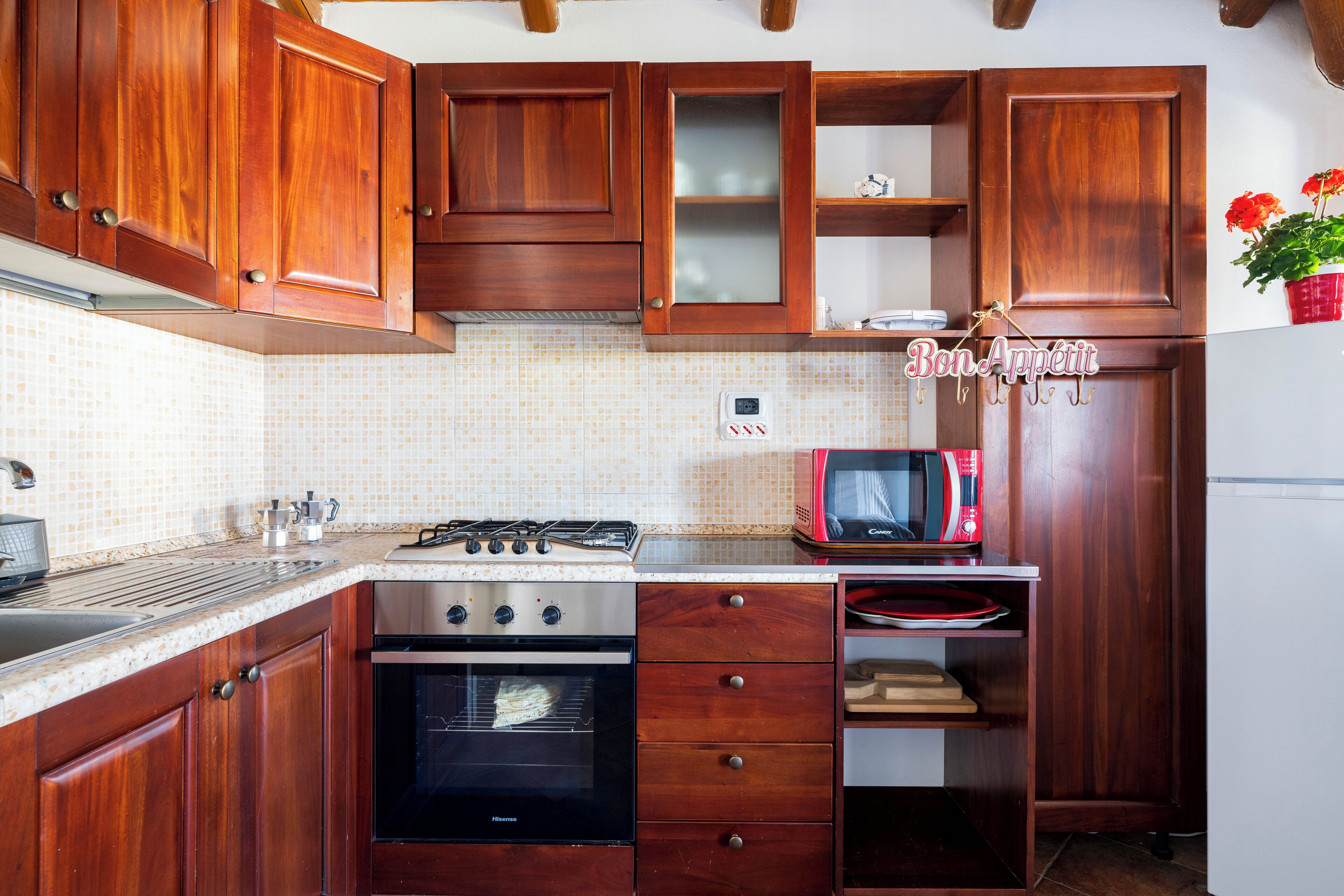 A kitchen with wooden cabinets, a gas stove, a microwave, and a refrigerator.