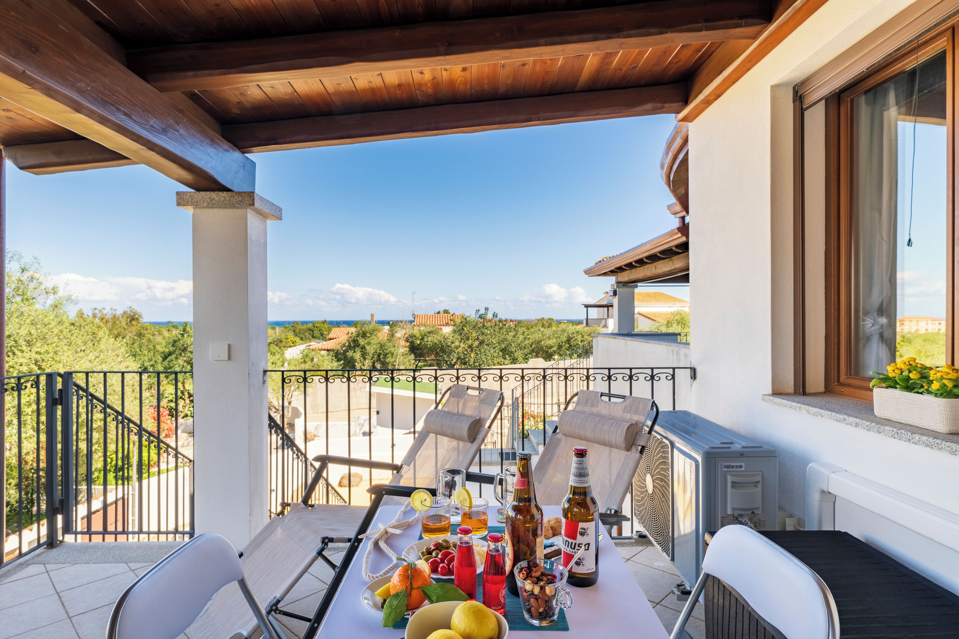 Un balcón con una mesa lista para comer, mobiliario de exterior y vistas del paisaje.
