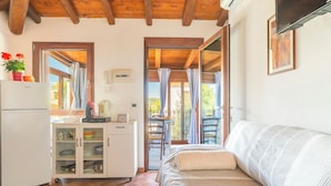 A cozy room with a bed, a kitchenette, and a balcony with curtains.