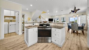 Een ruime keuken met een centraal eiland, inbouwapparatuur en een eethoek met een grote tafel en stoelen.
