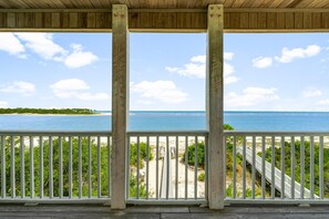 Un pontile di legno con ringhiera bianca che si affaccia su una spiaggia con una passerella in legno che conduce alla riva.