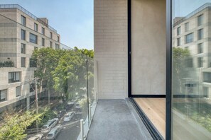 A modern building with a glass balcony overlooking a parking area and other buildings.