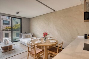 Une chambre moderne avec un grand lit, un canapé et un coin repas comprenant une table ronde et des chaises.