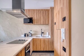Een compacte keuken met een ingebouwde magnetron, een koffiezetapparaat en een telefoon.