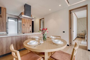 Une cuisine moderne dotée d’un îlot central, de meubles de rangement en bois et d’un coin repas avec une table ronde et des chaises.