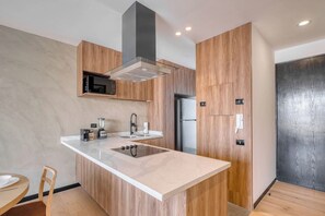 Une cuisine moderne dotée d’un îlot central, d’un four à micro-ondes encastré et d’appareils électroménagers en acier inoxydable.
