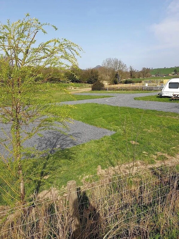 Un'area di parcheggio sterrata con un camper bianco parcheggiato a destra.