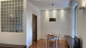 Un espace repas moderne avec une table et des chaises en bois, un banc et un téléviseur posé sur un meuble.