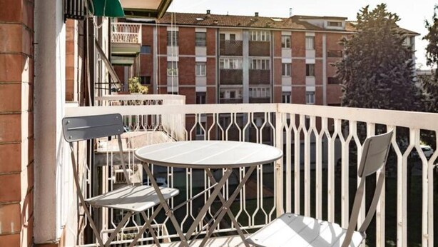 A balcony with a white metal railing, a round table, and two white chairs. - Accomodo MIT12 Trivano Linate  (Milan)