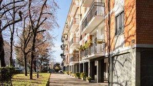 A row of multi-story residential buildings with balconies, a clear pathway, and trees. - Accomodo MIT12 Trivano Linate  (Milan)