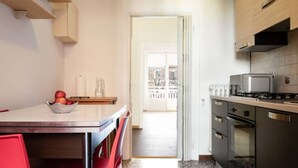 A kitchen with a dining table, chairs, a bowl of fruit, a stove, and an oven. - Accomodo MIT12 Trivano Linate  (Milan)