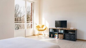 A bedroom with a bed, a television on a wooden cabinet, and a window with a view of trees. - Accomodo MIT12 Trivano Linate  (Milan)