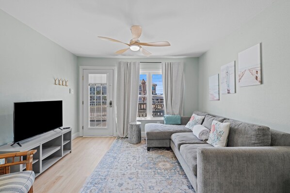 A living room with a flat-screen TV, grey sofa, and a ceiling fan. - Pet Friendly Updated Townhome sleeps 10! (Navarre)