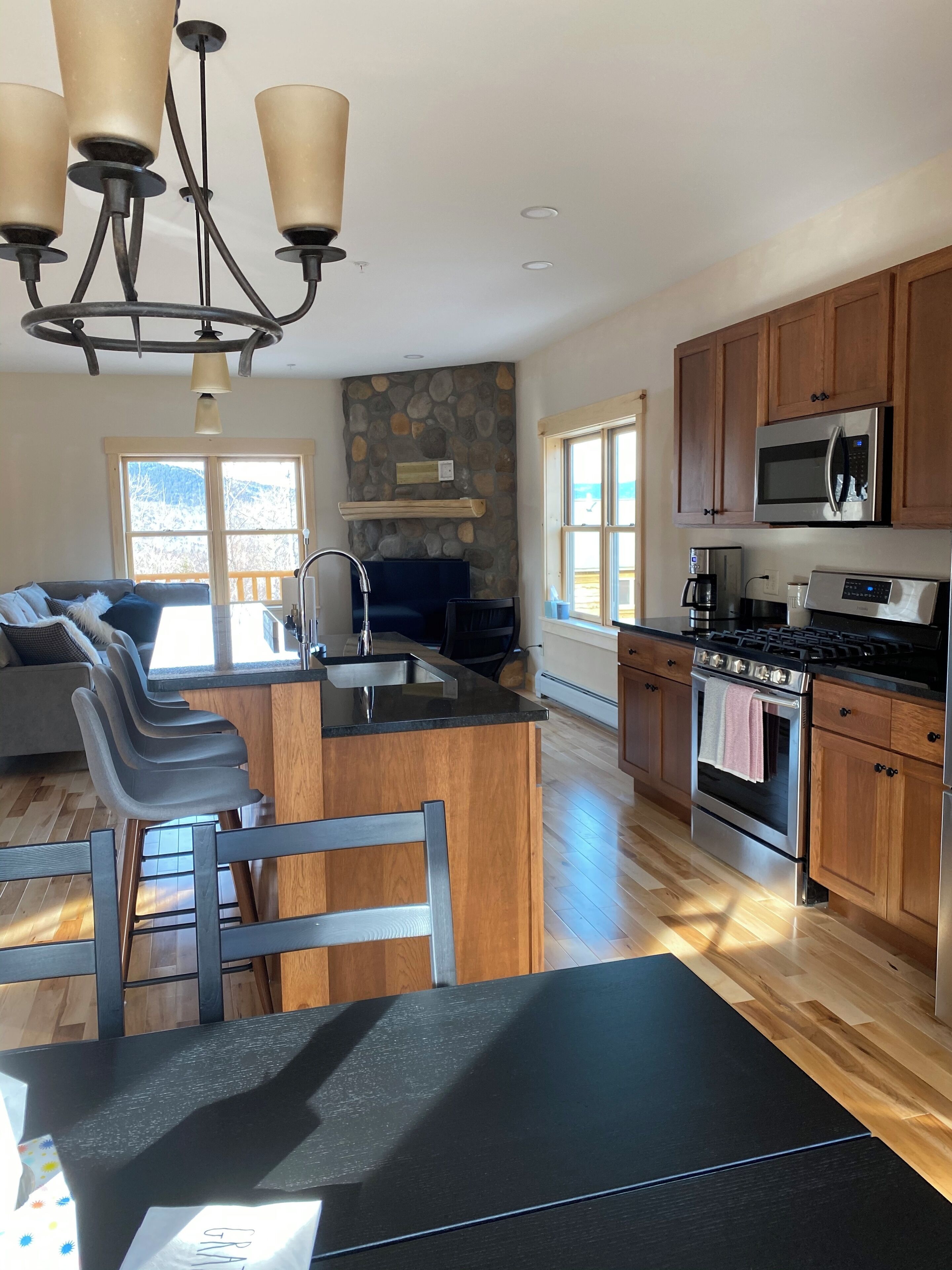 A modern kitchen with a central island, wooden cabinets, a built-in microwave, and a stove.