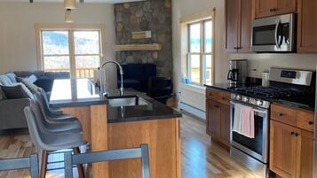 A modern kitchen with a central island, wooden cabinets, a built-in microwave, and a stove.
