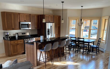 A modern kitchen with wooden cabinets, stainless steel appliances, and a central island with bar stools.