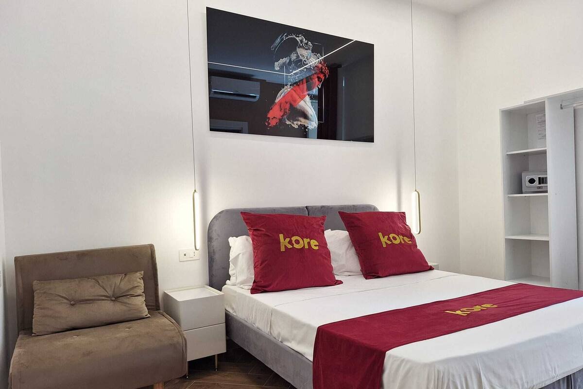 Una moderna camera d'albergo con un letto, una sedia, un comodino e un armadio.