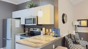 Une cuisine moderne dotée d’un îlot central, d’appareils électroménagers intégrés et d’un coin repas avec des chaises à motifs.
