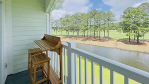 Une terrasse en bois avec une table et des chaises, donnant sur un lac et des arbres.