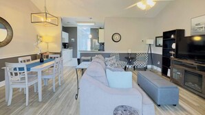 Un salon moderne comprenant un coin repas, un canapé, un téléviseur et un ventilateur de plafond.