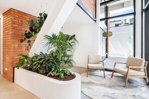Un intérieur moderne avec un mur en briques, un pot de fleurs blanc contenant des plantes et deux chaises.