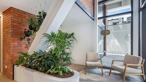 Un intérieur moderne avec un mur en briques, un pot de fleurs blanc contenant des plantes et deux chaises en bois.