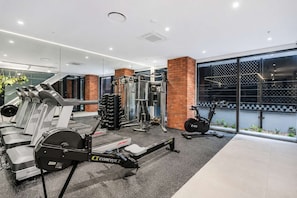 A modern gym with various exercise equipment, including treadmills, weight machines, and an elliptical.