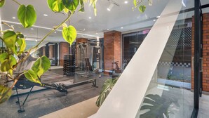 Een moderne sportschool met trainingsapparatuur, een glazen wand en binnenshuis planten.