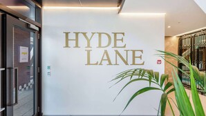 Een schoon, modern interieur met een opvallend 'HYDE LANE' bord aan de muur, een glazen deur en een potplant.