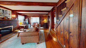 A spacious living room with a fireplace, wooden walls, and a staircase. - Gorgeous Waterfront Home in the Heart of North Kingstown (North Kingstown)