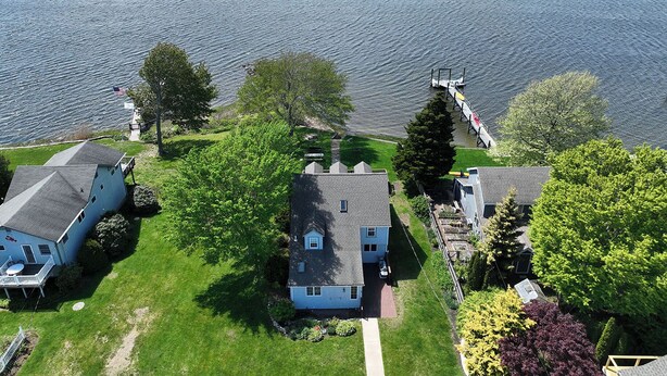 A residential area with houses near a large body of water, a dock, and a small boat. - Gorgeous Waterfront Home in the Heart of North Kingstown (North Kingstown)